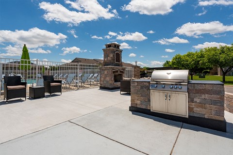 an outdoor patio with a barbecue grill and tables and chairs