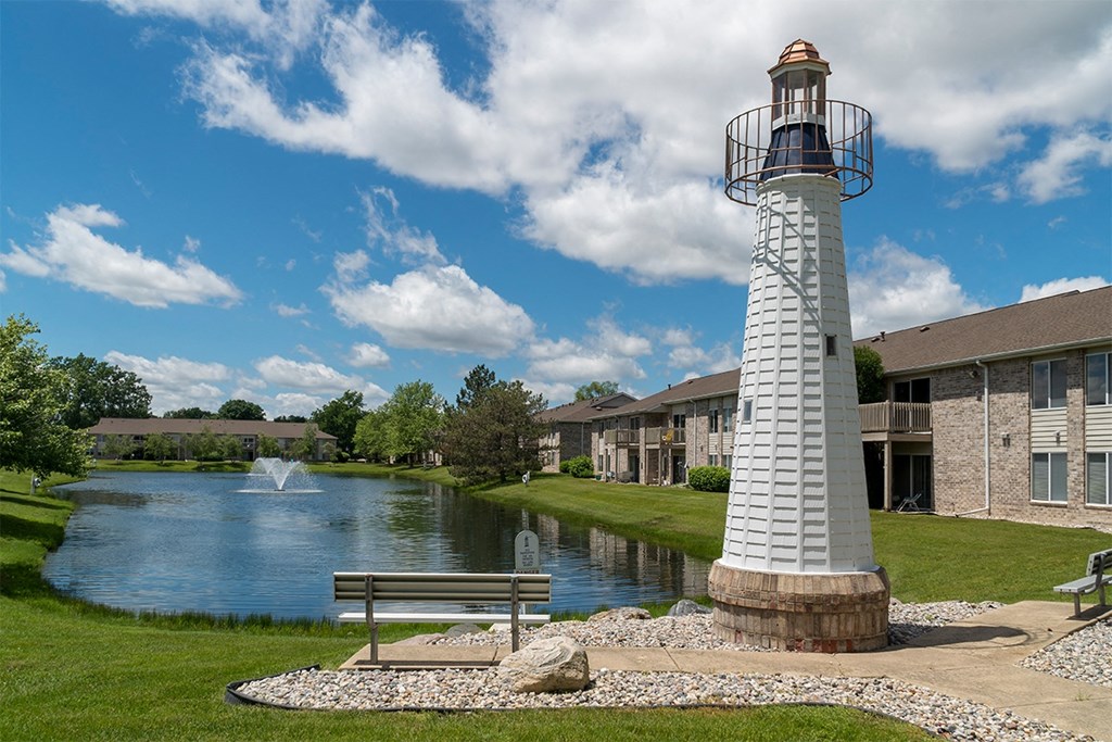 light house and a bench in front of a lake