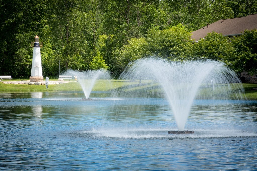 a fountain in the middle of a lake with a lighthouse