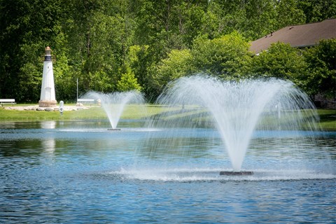 a fountain in the middle of a lake with a lighthouse