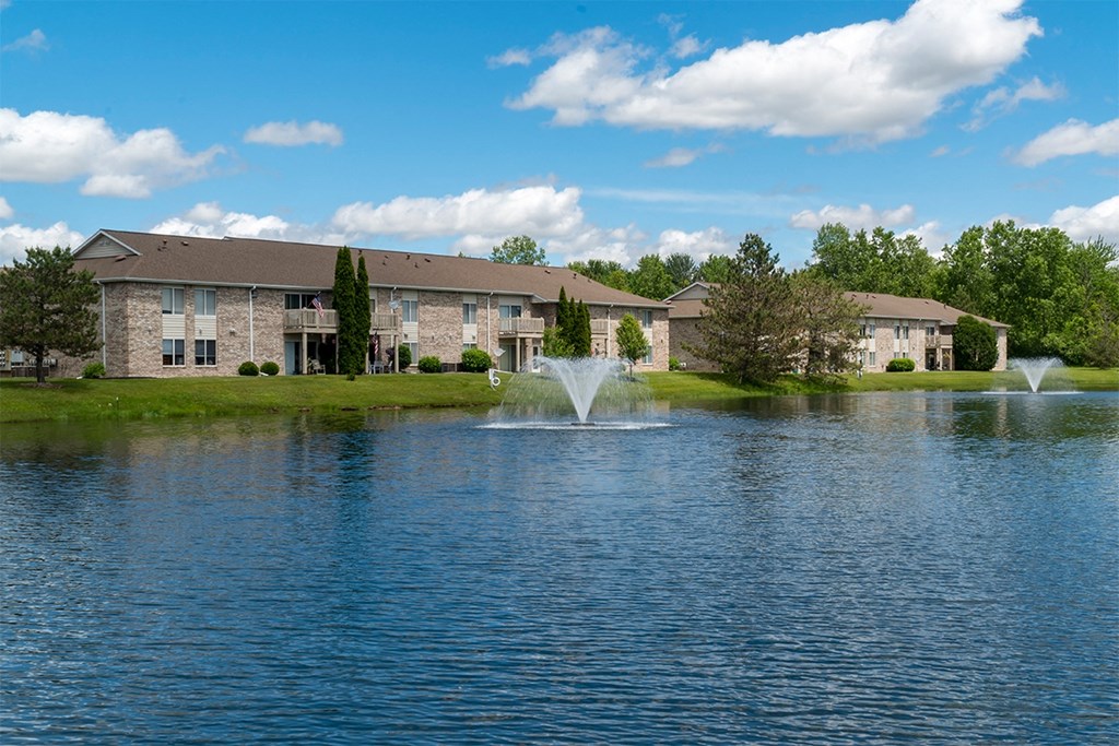a fountain in the middle of a lake with a building in the background