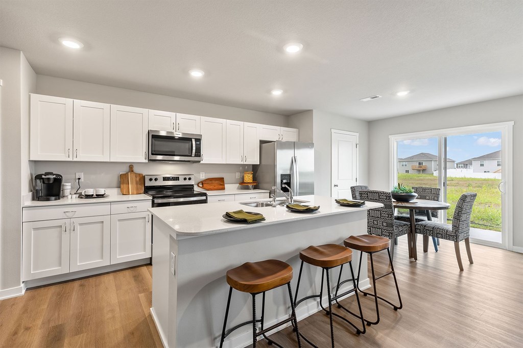A kitchen with white cabinets and a large island with bar stools.