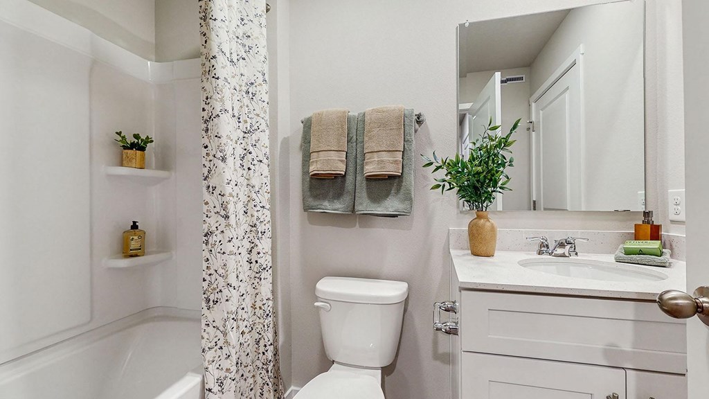A white bathroom with a toilet, sink, and shower.