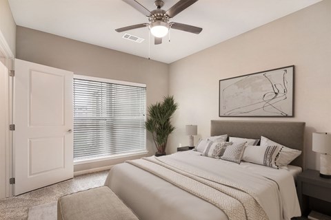 A bedroom with a large bed and a ceiling fan.