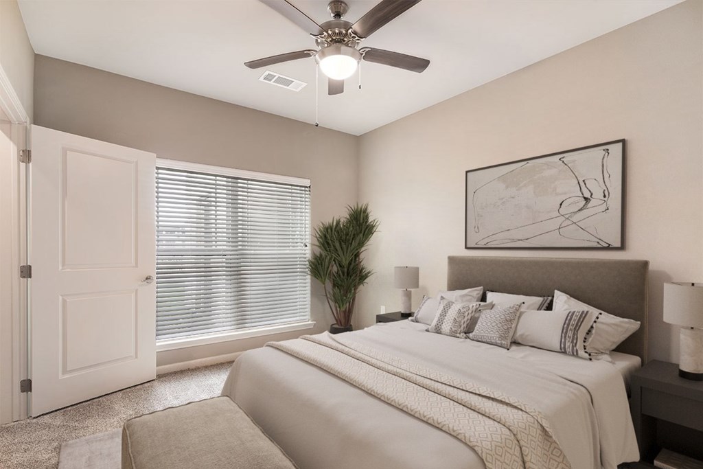 A bedroom with a large bed and a ceiling fan.