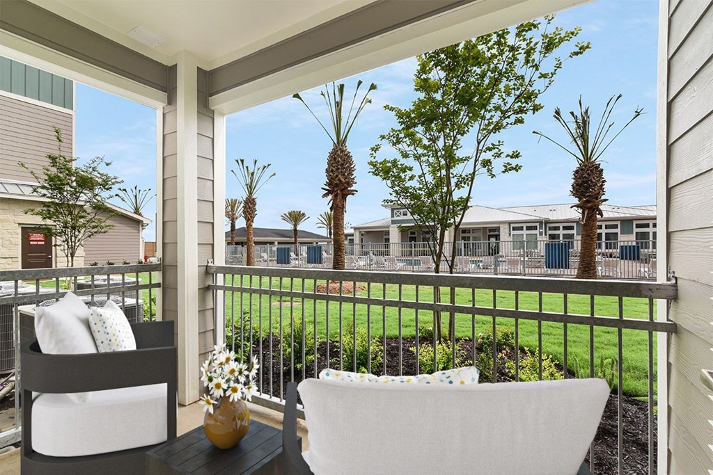 A patio with two chairs and a table with a vase of flowers on it.