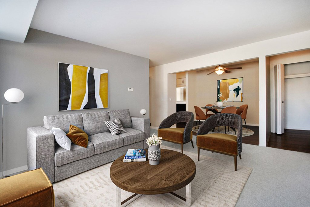 A living room with a grey couch, a coffee table, and a painting on the wall.
