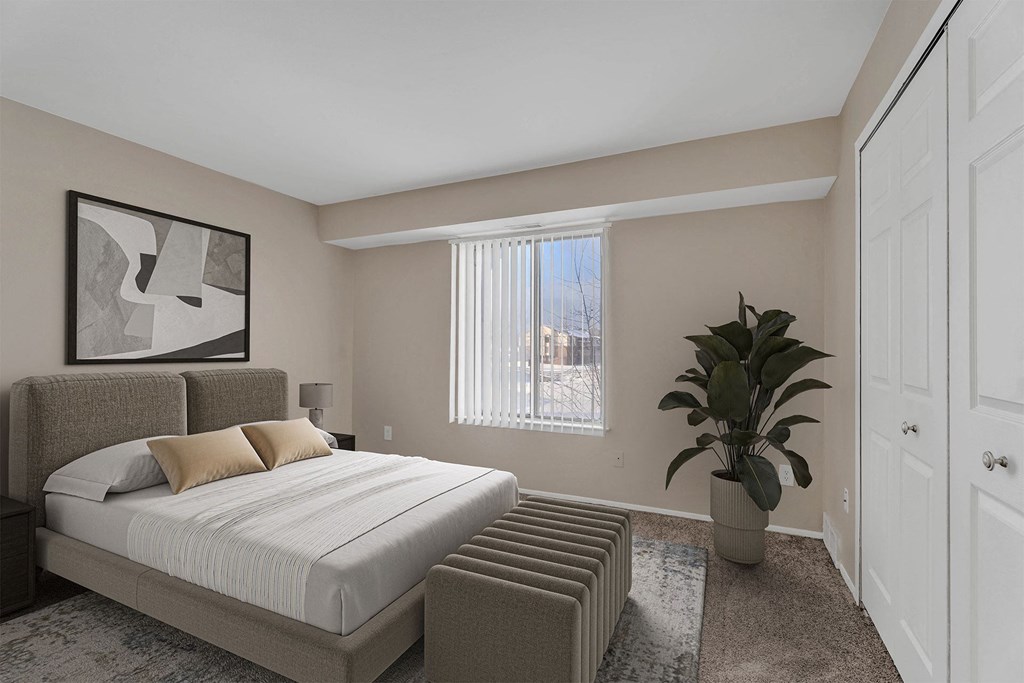 A bedroom with a large bed and a potted plant.