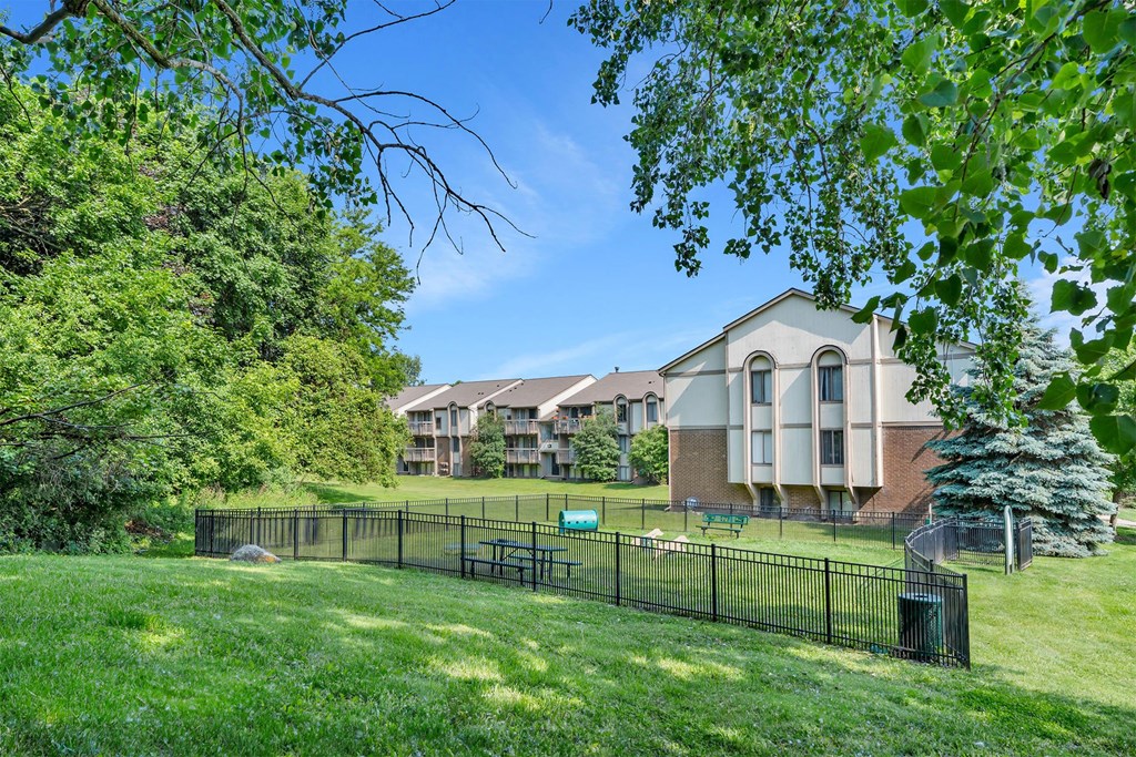 A large grassy area in front of a building with a black fence.