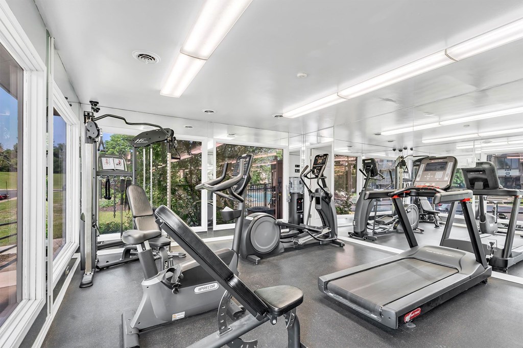 A well-lit gym with treadmills, exercise bikes, and other equipment.