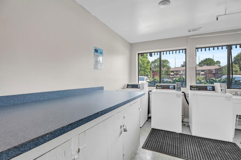 A clean, well-lit laundry room with washing machines and a counter.