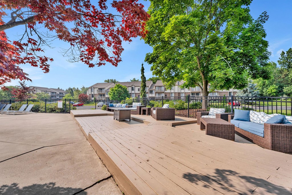 A wooden deck with a bench and trees in the background.