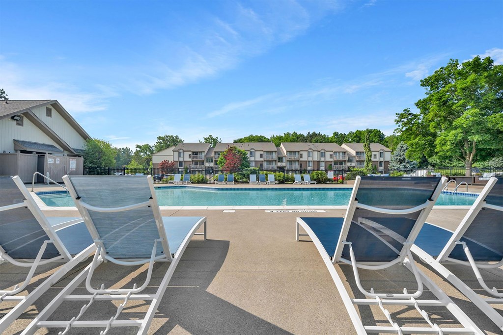 A pool surrounded by lounge chairs and trees.