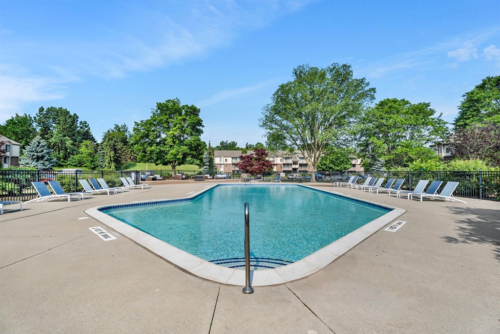 A large swimming pool surrounded by lounge chairs and trees.