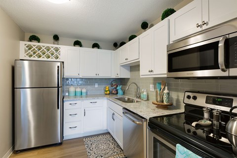 A kitchen with a stainless steel refrigerator and black stove top oven.