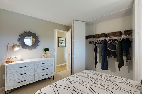 A bedroom with a white bed and a white dresser with a mirror above it.