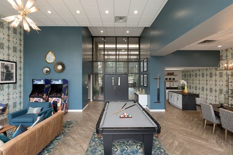A pool table is in the middle of a room with a blue wall and a patterned wallpaper.