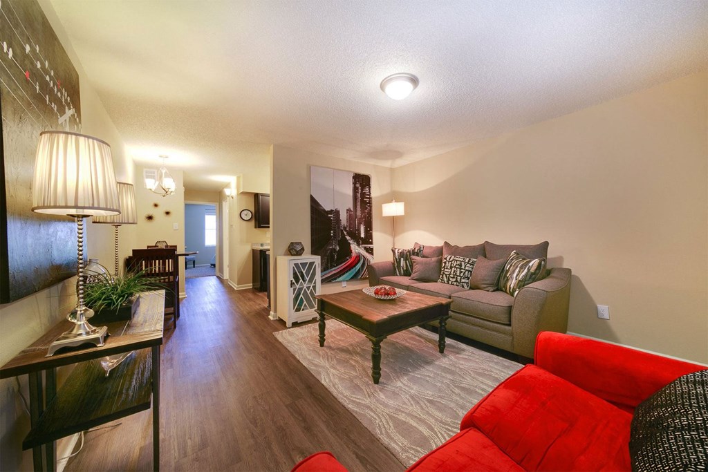 A living room with a red couch and a wooden coffee table.