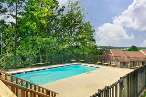 A pool surrounded by a fence and trees.