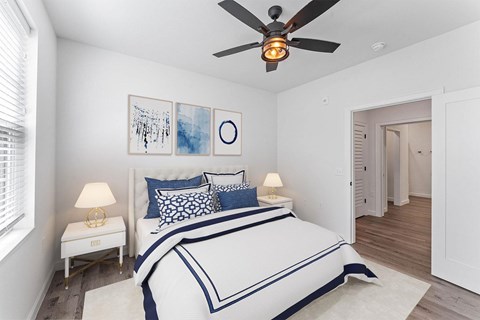 A bedroom with a bed, two lamps, and a ceiling fan.