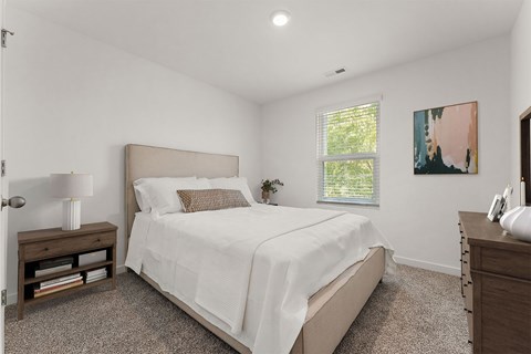 A bedroom with a large bed and a window with blinds.