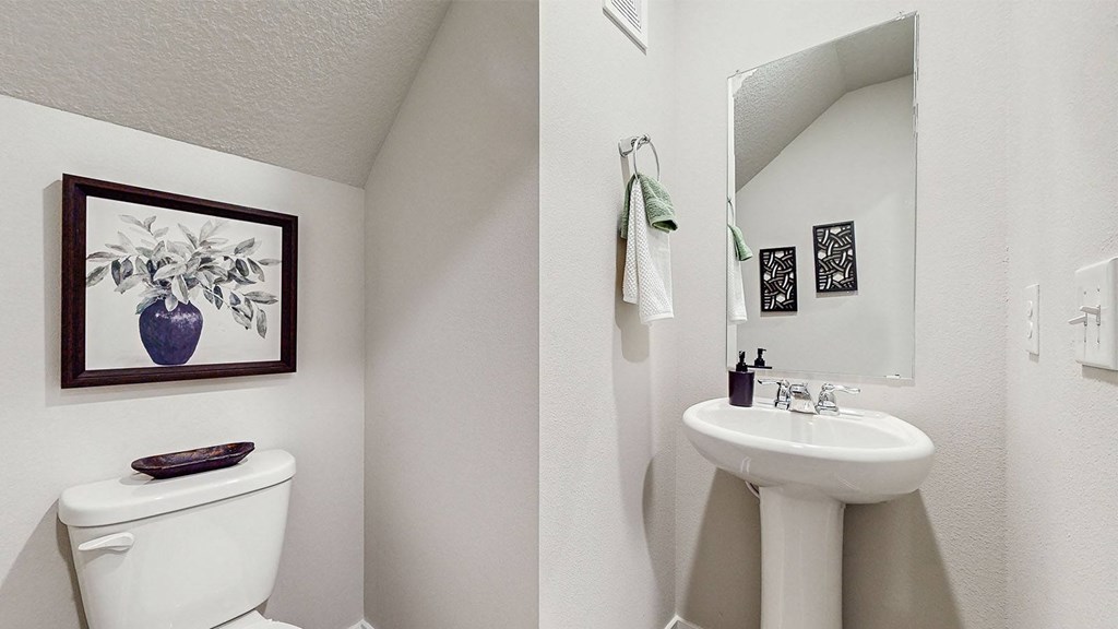 A white toilet sits next to a white sink in a small bathroom.