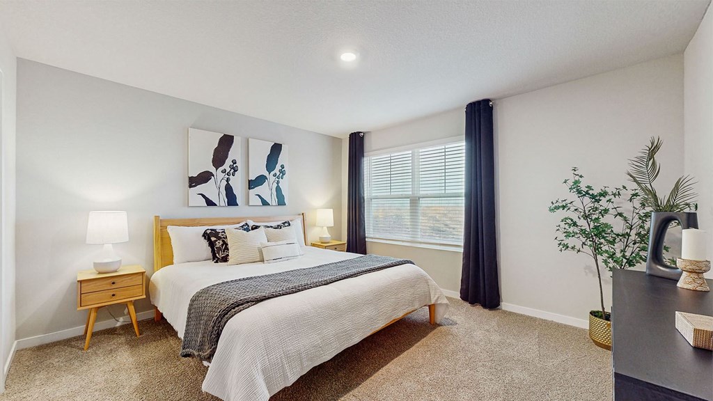 A bedroom with a bed, nightstand, and a painting on the wall.