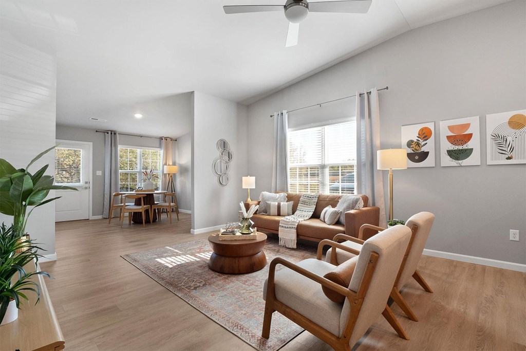 A living room with a brown rug, a wooden coffee table, and a fan on the ceiling.