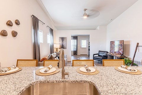 A kitchen with a sink, counter and chairs.