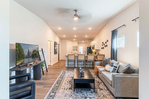 A living room with a grey couch, a black coffee table, and a painting of a landscape on the wall.