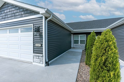 A house with a grey garage door and a white door.