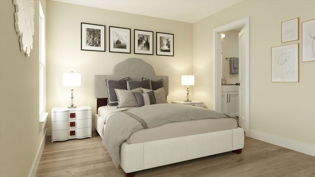 A bedroom with a large bed and a nightstand with a lamp.