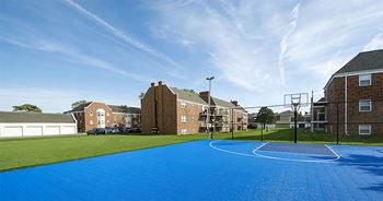 a blue basketball court in front of a row of brick houses