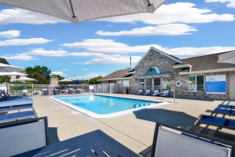 A pool area with sun loungers and a building in the background.
