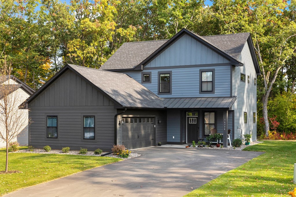the front of a gray house with a black garage door