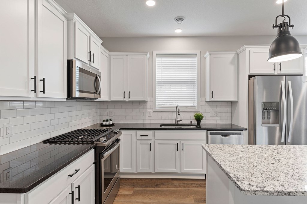 A kitchen with white cabinets and a black stove top.