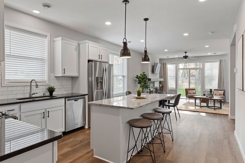 a kitchen with a center island and bar stools in front of a dining room