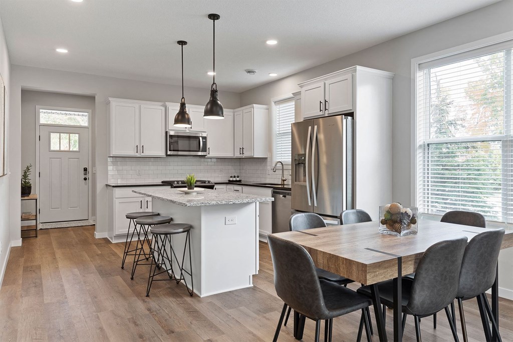 a kitchen and dining room with white cabinets and stainless steel appliances