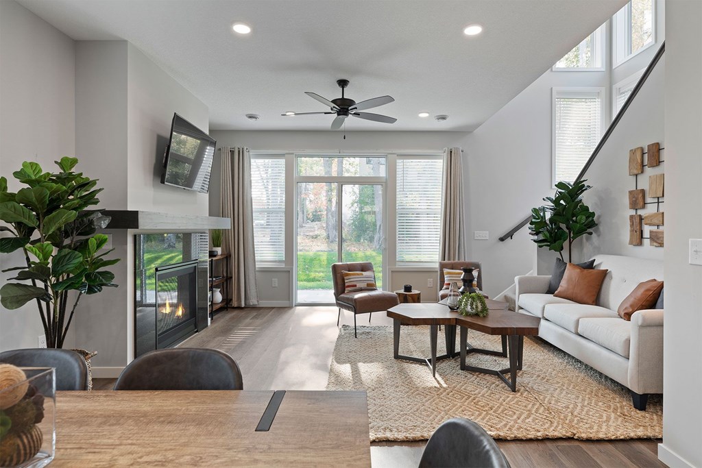 A modern living room with a fireplace and a ceiling fan.