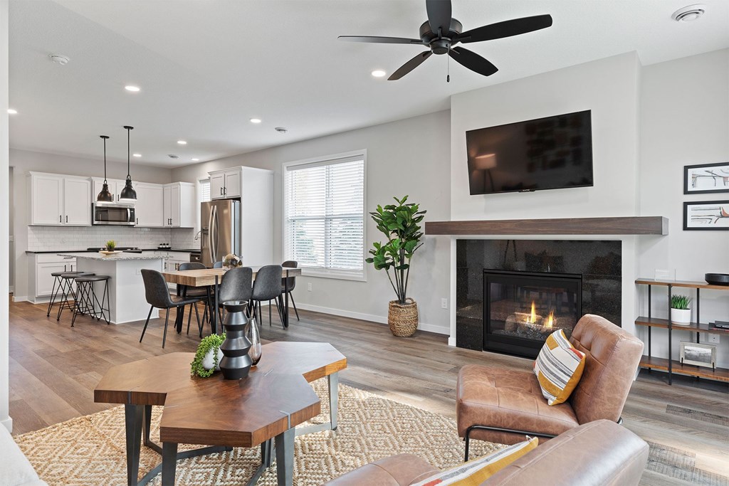 A modern living room with a fireplace and a dining area in the background.