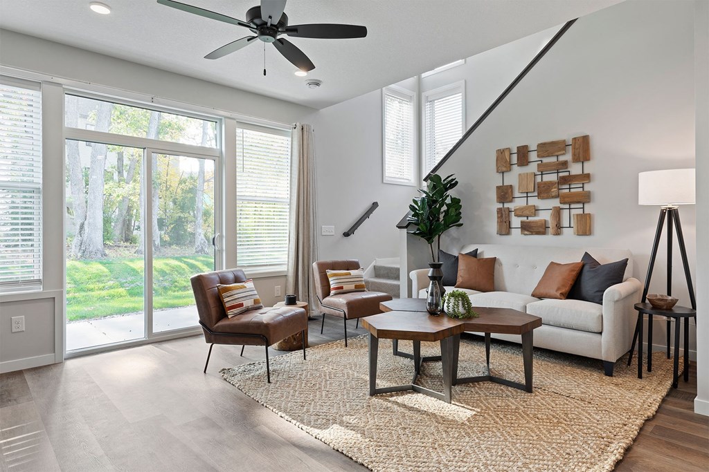 a living room with a couch and chairs and a ceiling fan