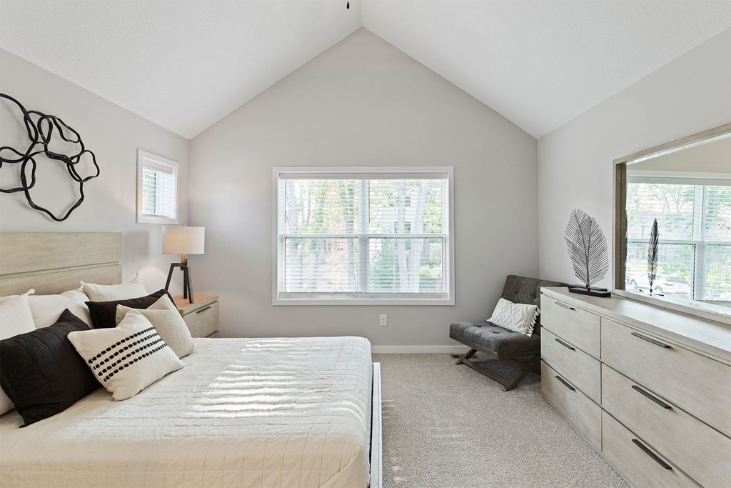 A bedroom with a large bed, a window with a view, and a bench.