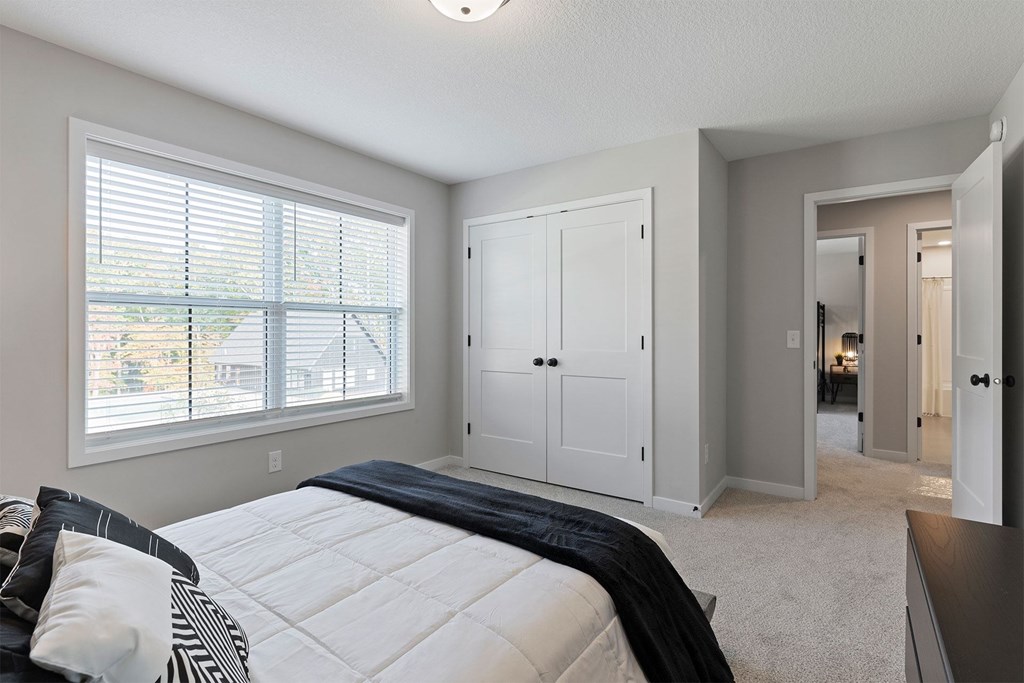 A bedroom with a large bed and a window with blinds.