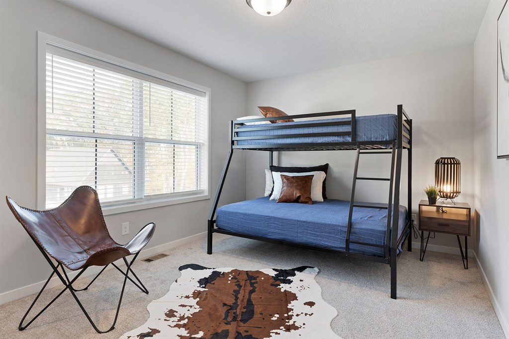 A room with a bunk bed and a chair.