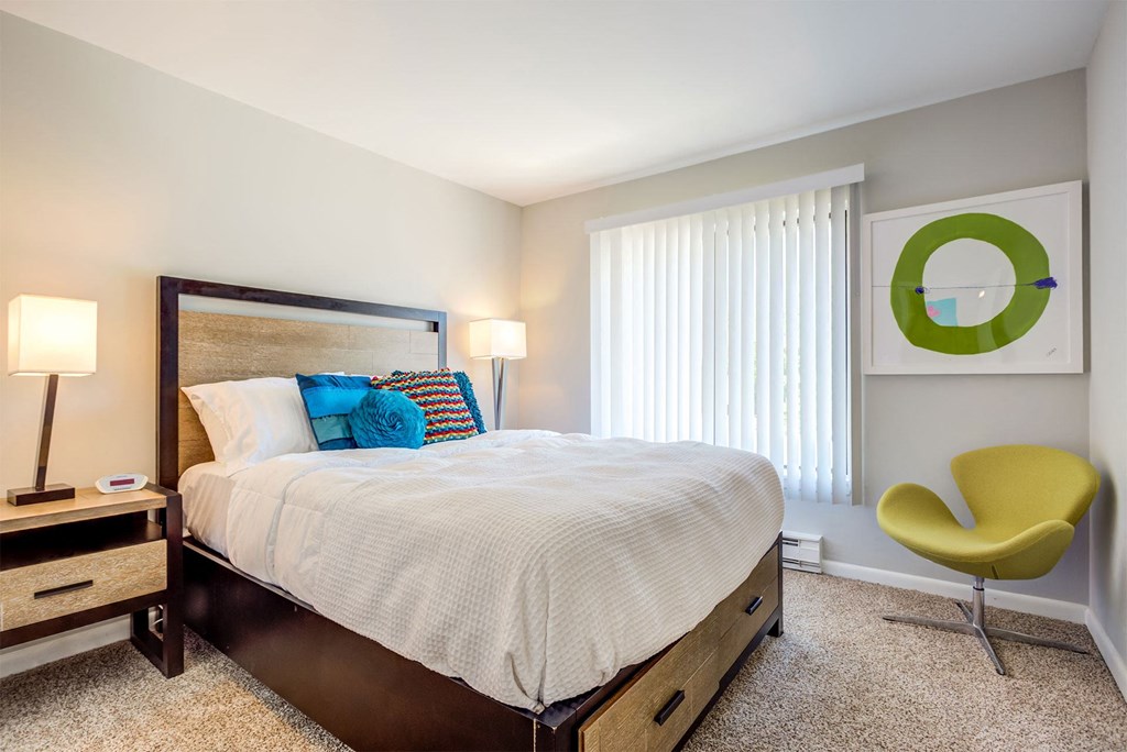 a bedroom with a bed and a chair and a window