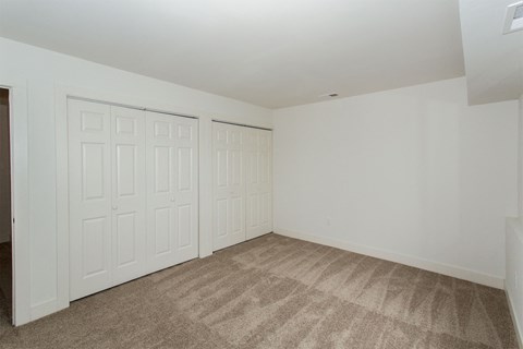 a bedroom with two closets and a carpeted floor