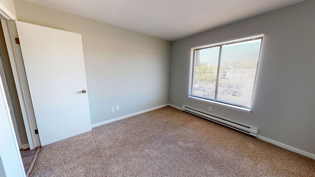 a bedroom with a large window and carpeted floor