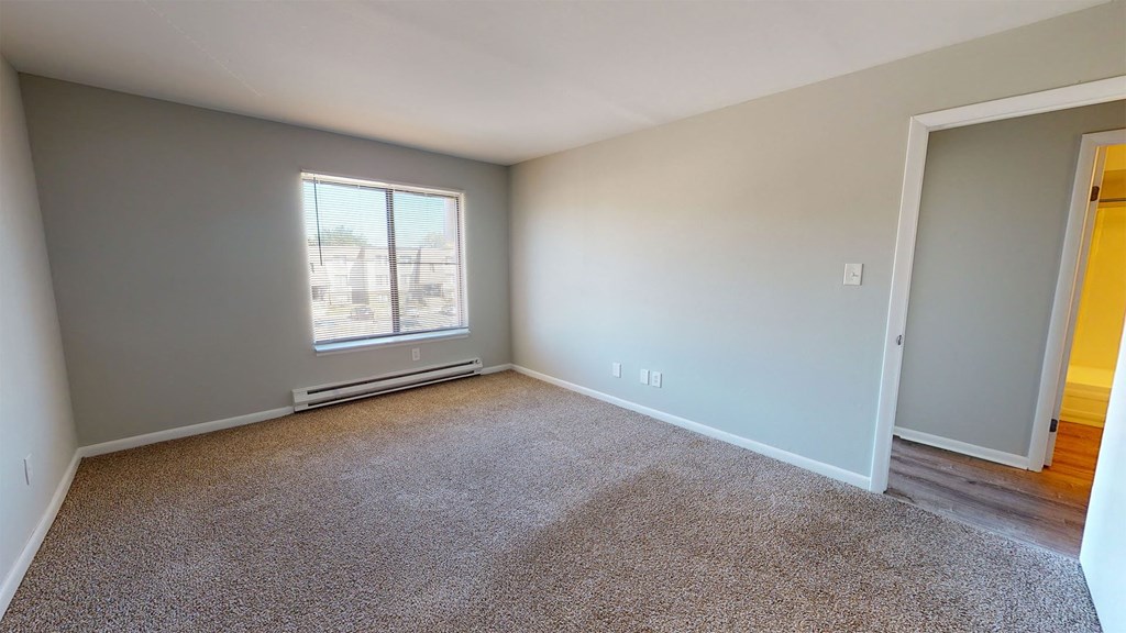 an empty living room with a window and carpet