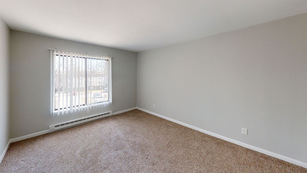 an empty bedroom with a window and carpet