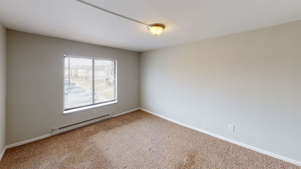 an empty living room with a window and carpet